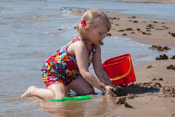 Lapsi leikkii hiekkarannalla