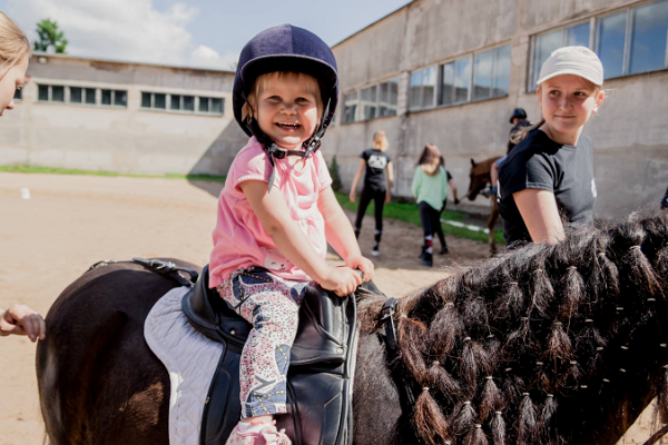 Väike laps ratsutab poni seljas