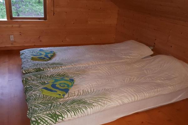 Jõesuun majatalon saunarakennuksen huone, jossa on kaksi sänkyä