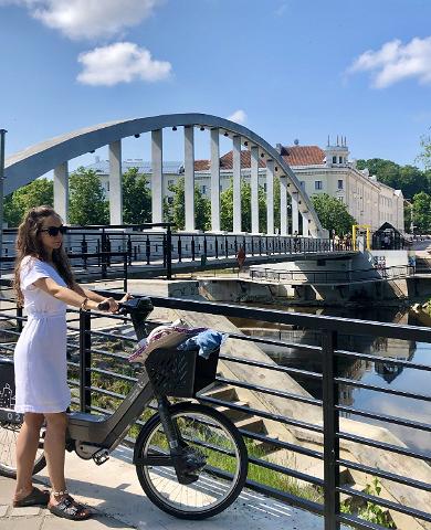 Arch Bridge and a girl standing next to a bike of the Tartu bike sharing circuit