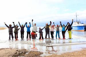 Группа участников похода на финских санях, машет фотографу