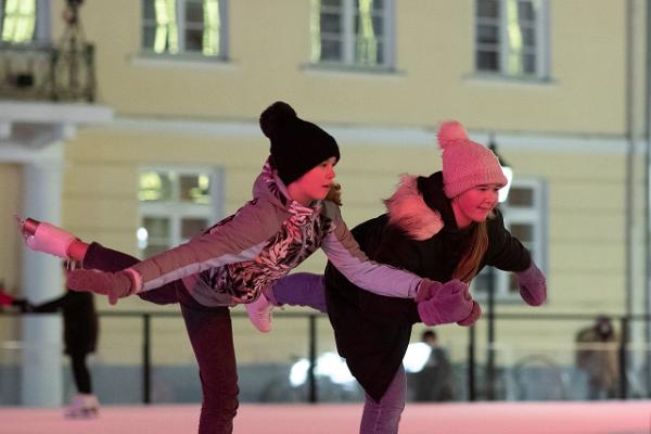 Schlittschuhbahn im Stadtzentrum von Tartu: fröhliche Schlittschuhfahrer machen Tricks auf dem Eis