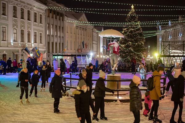 Fröhliche Schlittschuhfahrer und die Schlittschuhbahn in der Innenstadt von Tartu