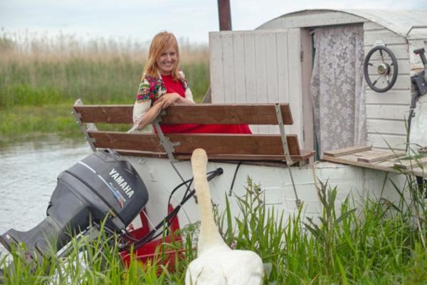 The hostess of Mesi tare guesthouse sitting in a boat house and talking to a swan