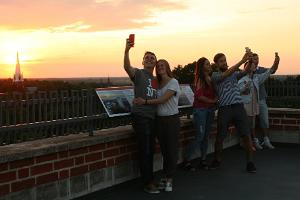 Tartu Universitātes muzejs, doma baznīcas torņi,
jaunieši saulrietā uzņem selfijus
