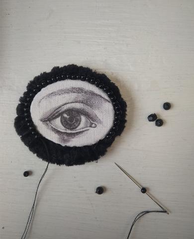 Pooleliolev silma motiiviga tekstiilist pilt, must-valge pross. Autor Maris Aare