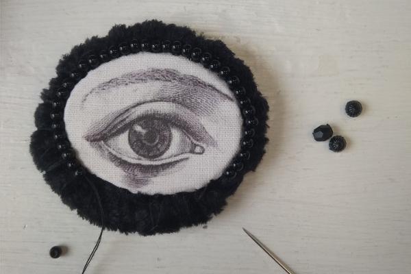 Pooleliolev silma motiiviga tekstiilist pilt, must-valge pross. Autor Maris Aare
