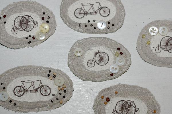 Linased erinevate jalgratastega tekstiilist nööpide ja pärlitega kaunistatud prossid. Autor Maris Aare
