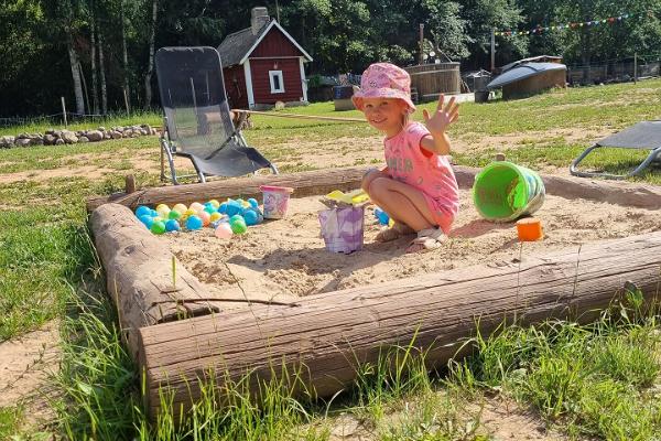 En flicka som leker i sandlådan på djurparken på Nugise hobbygård