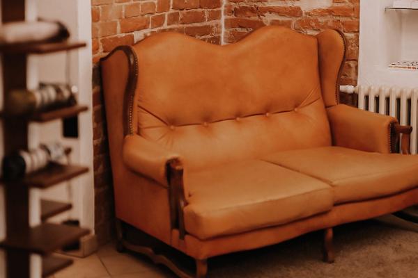 cognac-colored vintage leather sofa in the corner of the brick wall